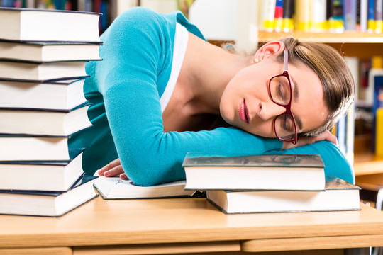 女学生在图书馆看书学习，她睡着了，又累又累