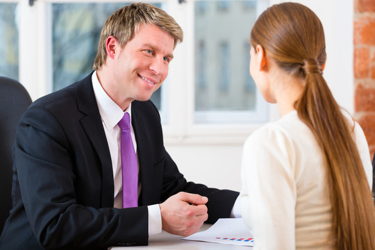 年轻律师、保险代理人或律师在其办公室工作，并与女性客户或客户进行咨询