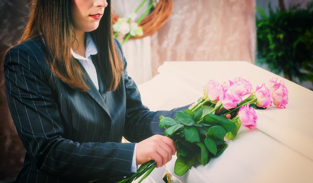 葬礼上把玫瑰放在棺材上的女人
