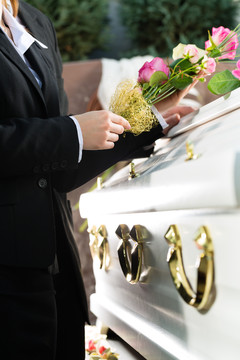 葬礼上的哀悼男女站在棺材或棺材前的粉红玫瑰