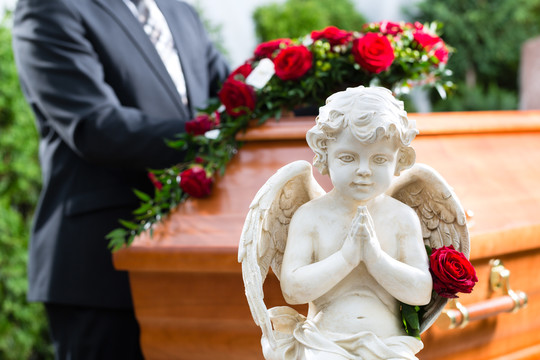 葬礼上的哀悼者站在棺材或棺材前，手持红玫瑰