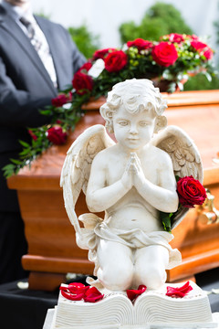 葬礼上的哀悼者站在棺材或棺材前，手持红玫瑰