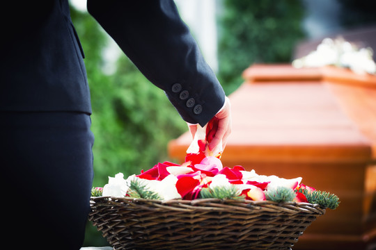 葬礼上的女人把玫瑰花瓣放在棺材上