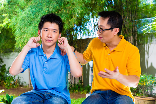 亚裔华裔父亲对儿子说话却不听，用手捂着耳朵拒绝好话