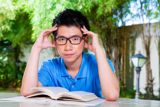 年轻的亚裔中国学生在家里对第二天学校布置的难做的家庭作业感到厌烦