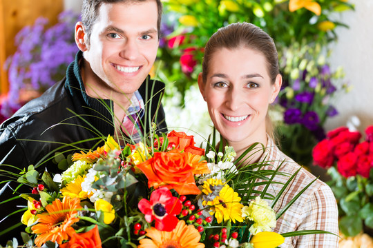 在花店或苗圃里献一束花的女花匠和顾客