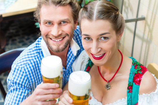 年轻夫妇在传统的巴伐利亚小吃店或酒吧与啤酒