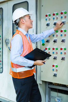 亚裔印尼技术人员或电工在施工现场或工厂对空调控制面板或开关箱进行功能测试验收