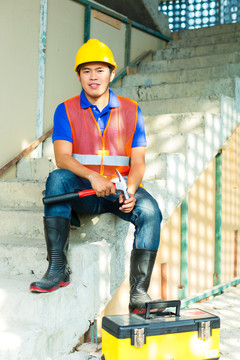 在亚洲的一个建筑工地上，戴着头盔和安全背心的亚裔印尼建筑工人