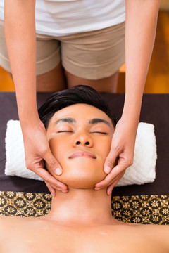 印尼亚裔男子在健康美容spa有芳香疗法面部按摩精油，看起来轻松