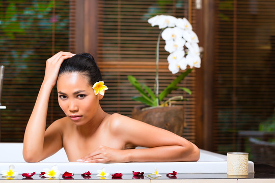 印尼亚裔女子在健康美容日温泉浴场用精油或盐进行芳香疗法浴，看起来很放松
