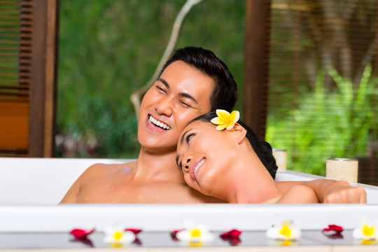 印尼亚裔夫妇在健康美容日水疗中心用精油或盐进行芳香疗法浴，看起来很放松