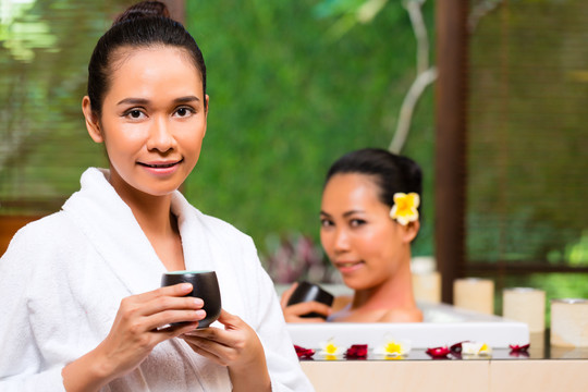 印尼亚裔妇女在健康美容日水疗中心享受芳香疗法浴和喝凉茶排毒