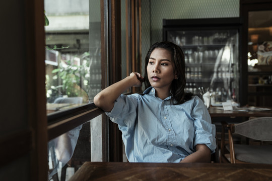 一名泰国亚裔女子坐在咖啡馆里等待食物。