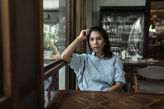 一名泰国亚裔女子坐在咖啡馆里等待食物。