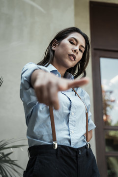 特写镜头中，身着蓝色连衣裙的泰国亚裔女子在镜头前用手指指着镜头。