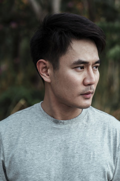 灰色衬衫上的亚洲成年男子特写肖像。亚洲年轻人的头像。