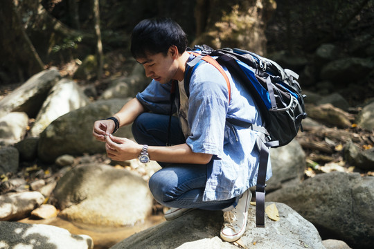 男性徒步旅行者坐在岩石上休息片刻。