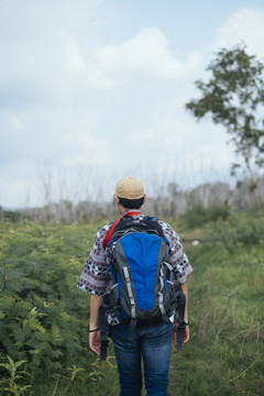 行走在有树、湖、山的自然小径上的男性冒险家。