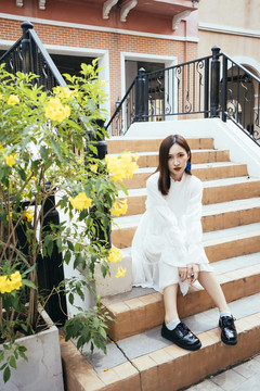 美丽的长发白衣女孩坐在桥的楼梯上。