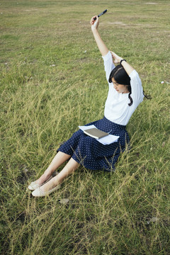 年轻的亚洲小说作家坐在草地上，在完成小说《新故事时间轴》后伸展四肢。