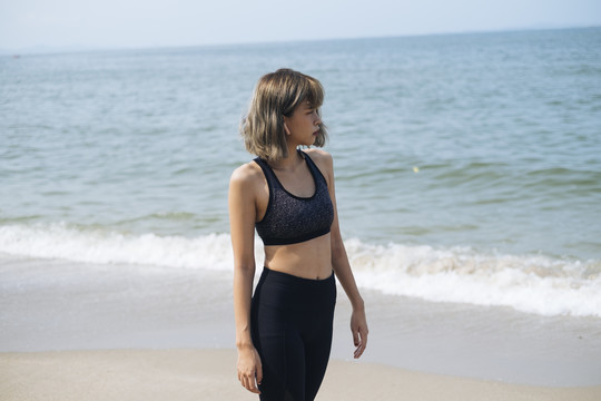 短发运动型女子在沙滩上伸展身体、做瑜伽，在沙滩上慢步行走。