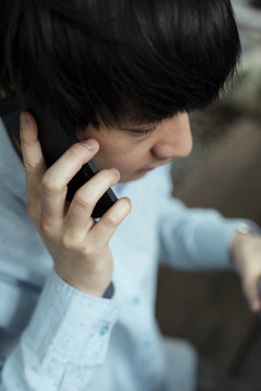 剪短的图像高角度拍摄的黑发男子在蓝色衬衫得到的电话。