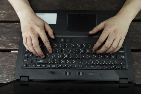 裁剪后的照片是一个人的手在笔记本电脑上打字的俯视图。