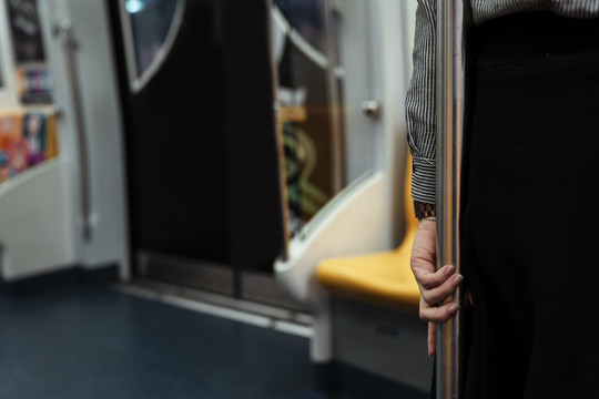 站在火车上的女人手抓着一根杆子的后视图。