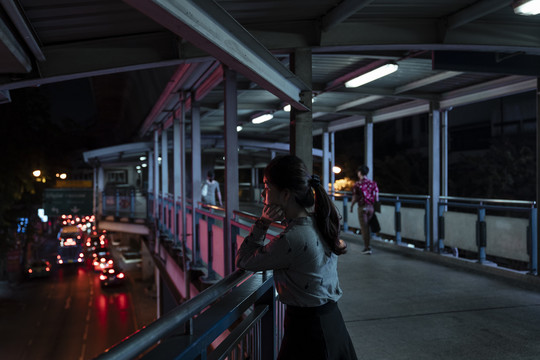 亚泰妇女站在天桥上看路。