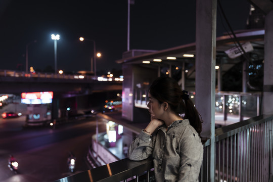 一名亚裔泰国妇女在路上等待有人在晚上接她。