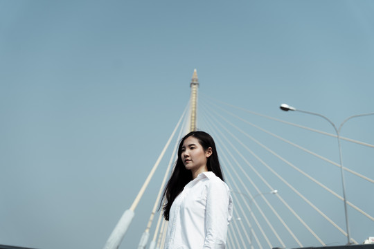 一个女人独自站在这座独特的桥前的晴空中。