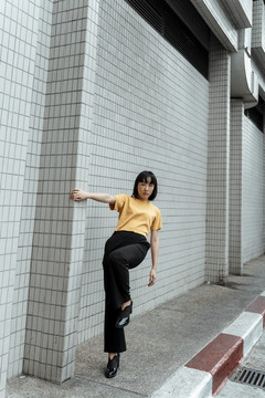 年轻的泰国亚裔女子深色短发穿着橙色衬衫，单腿站在街上。运动员生涯。