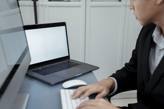 穿着黑西装在电脑上工作的亚洲商人在看笔记本电脑的复印空间
