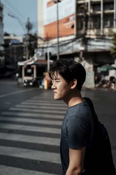 曼谷，英俊的游客走过马路的侧视图。