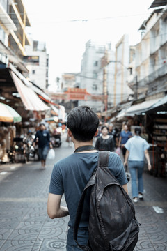 垂直后视图拍摄-年轻英俊的亚洲男子走在街头市场在曼谷。