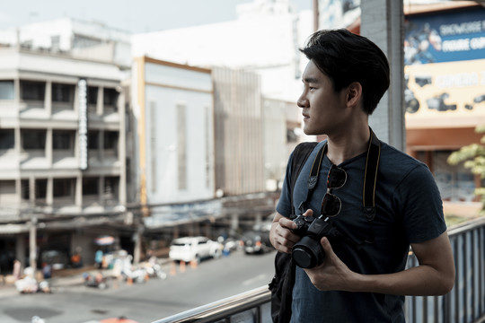 复制空间-年轻英俊的亚洲摄影师男子行走在曼谷市。