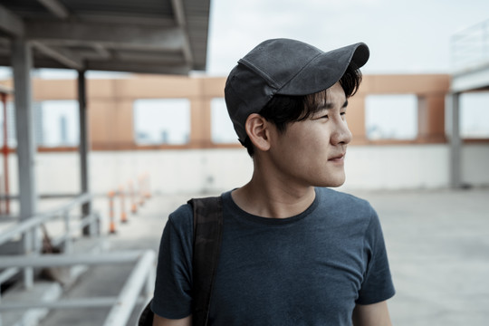 年轻的亚洲旅游者戴着帽子在城市里旅行