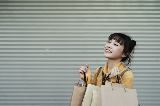 亚洲女人喜欢拿着隔离在穿梭门上的纸袋购物。