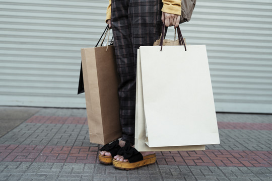 购物理念——年轻模特手拿购物纸袋。复制购物袋上的空间。