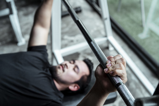 运动员亚泰体育男子闭着眼睛在健身房的杠铃台上练习。