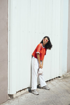 时尚写真-年轻迷人的亚泰女性深色头发，红色衬衫，白色墙壁上戴着时尚眼镜。