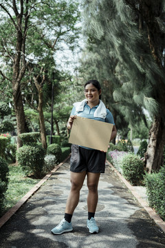 复制空间-胖乎乎的运动型亚洲女子穿着蓝色运动服手持空白杯板。