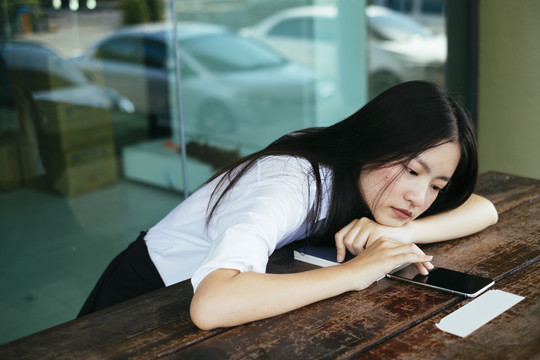 不开心美丽的深色长发年轻大学生身着制服在智能手机屏幕上触摸。