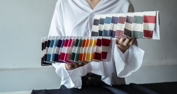 色彩缤纷的泛色调布料。色彩鲜艳的针织棉毛/纱线。拿着pantone颜色选择的女人。