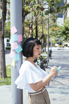 在街上记笔记的亚洲女商人。