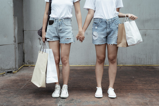 LGBTQ女同性恋者穿着休闲装，手拿纸袋。购物理念。