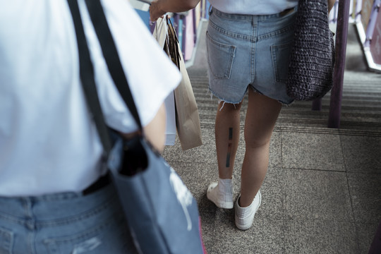 LGBTQ女同性恋者穿着休闲装，拎着购物袋走下楼梯。