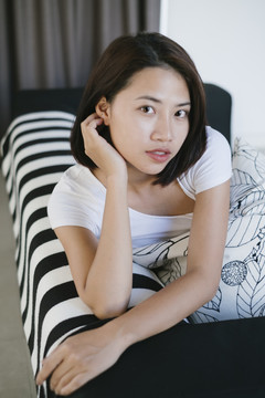 性感的亚泰女人在白色衬衫躺在客厅沙发上的肖像。