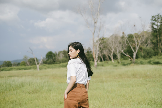 黑色长发女人穿着休闲服站在草原上度假。